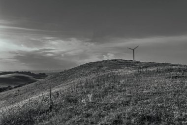 wind turbine in the middle of green field with a beautiful cloudy sky.