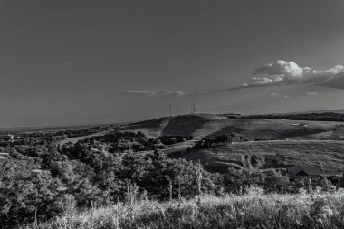 a grayscale shot of an empty road with a cloudy sky background