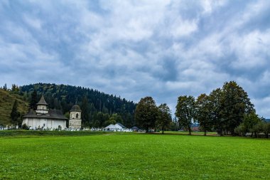 St. Michael Kilisesi 'nin dikey görüntüsü. Ormanın ortasında, dağların ortasında yeşil bir çayırın ortasında.