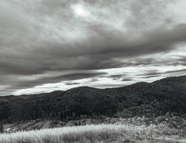 Bulutlu gökyüzünün altında dağların ve tepelerin güzel bir görüntüsü.