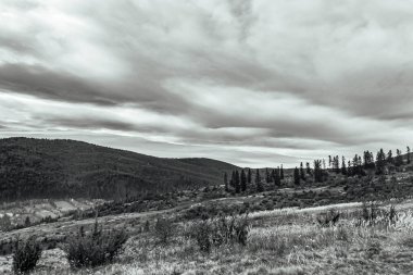 Dağların üzerinde siyah beyaz bulutlar