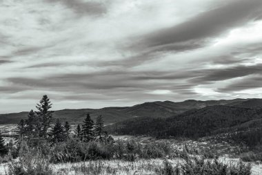 Dağların tepelerinde siyah ve beyaz bulutlar