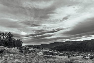 Karpat dağlarındaki bir dağ yolunda siyah beyaz bulutlar.