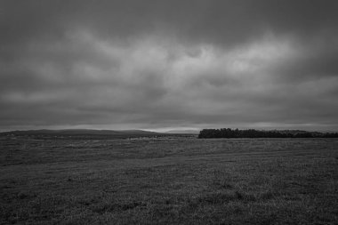 Siyah ve beyaz kırsal alanların üzerindeki karamsar bulutlar