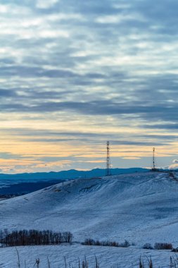 Kış günbatımında karlı bir tarla - tepeli zirveler
