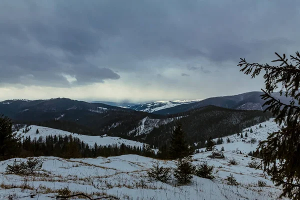 a vertical shot of a snowy mountain range under the cloudy sky