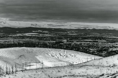 Karla kaplı dağların siyah beyaz görüntüsü ve arka planda bulutlu bir gökyüzü..