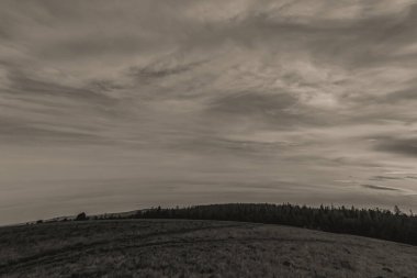 Sonbaharda bir dağ sırasının önündeki çimlerin gri tonda kapanışı.