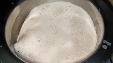 Kahve potada yavaşça kaynıyor. Alışveriş merkezi kabarcıkları yüzeyden yükseliyor. Buhar yükseliyor, sıcak bir koku yayıyor. Koyu kahverengi kahve içmeye hazır görünüyor..