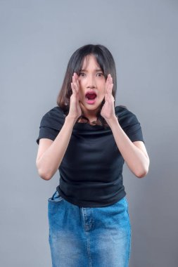 Şaşırmış bir suratı olan Asyalı bir kadın iki eli ağzının kenarında bağırıyor. Görüntü, modern yaşam tarzında iletişim, aciliyet, duyuru ve duygusal tepkiyi temsil ediyor..