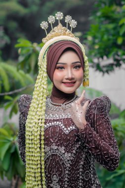 Üzerinde yasemin çiçeği çelengi, altın taç ve kına sanatı olan kahverengi kebaya bürünmüş Endonezyalı güzel bir kadının portresi. Zengin kültür mirasını temsil eden geleneksel moda..