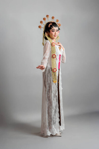 Indonesian bride in Solo Putri attire, wearing a golden headdress, jasmine garlands, and a white lace kebaya. She radiates grace and elegance with a soft, confident smile.