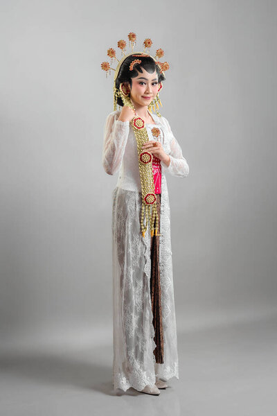 Indonesian bride in Solo Putri traditional attire, wearing an intricate golden headdress, jasmine garlands, and a white lace kebaya. She exudes elegance with a soft, graceful smile.
