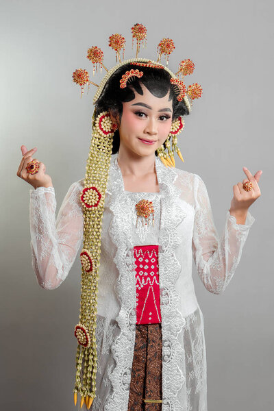 An elegant Indonesian bride in traditional Solo Putri attire, wearing a lace kebaya, intricate golden accessories, and jasmine garlands, smiling gracefully.