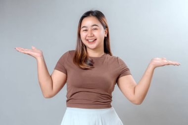 Gülümseyen ve iki elini de kaldıran neşeli genç bir kadın arkadaşlığı ve pozitifliği ifade ediyor. Tarafsız bir arkaplanda izole edilmiş, reklam ya da promosyon için ideal..