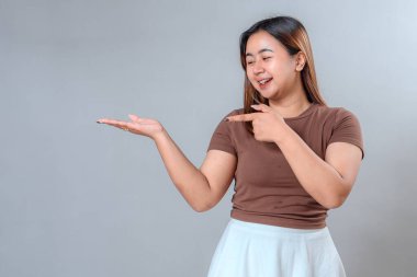 Gülümseyen genç bir kadın açık elini, promosyon içeriği, reklam afişleri veya pazarlama sunumları için uygun, davetkar ve dostane bir ifadeyle gösteriyor..