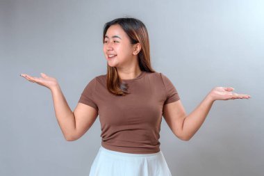 Neşeli bir gülümseme ile yana bakan genç bir kadın ve eğlenceli, anlamlı bir jest ile ellerini kaldırdı, heyecan ve pozitiflik gösteriyordu, reklam ve pazarlama için mükemmeldi..