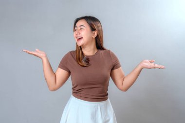 Neşeli bir gülümseme ile yana bakan genç bir kadın ve eğlenceli, anlamlı bir jest ile ellerini kaldırdı, heyecan ve pozitiflik gösteriyordu, reklam ve pazarlama için mükemmeldi..