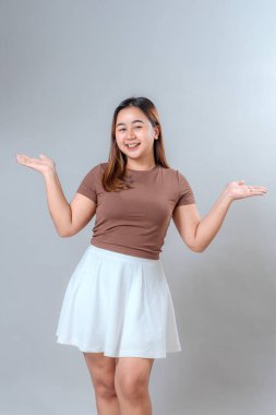 Gülümseyen genç bir kadın, iki eli havada ve açık, neşeli ve misafirperver bir yüz ifadesi sergiliyor. Promosyon içeriği, sunumlar veya reklamlar için ideal.