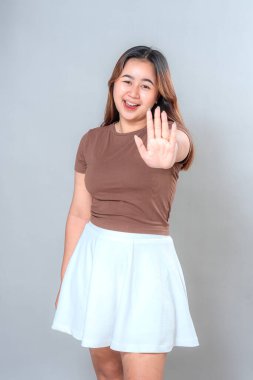 Asyalı genç bir kadın ciddi bir yüz ifadesiyle dur işareti yapıyor. Gözler odaklanmış, dudaklar büzüşmüş ve eller yukarı kalkmış. Reddetme, uyarı, reddetme ve kişisel sınırlar.