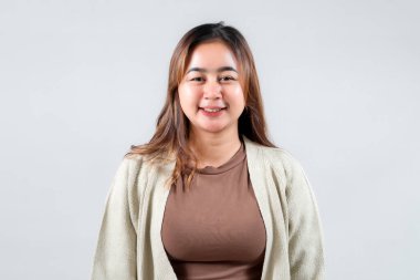 Neşeli genç bir kadın, tarafsız bir arkaplana karşı güvenle gülümsüyor, gündelik tarzını sergiliyor. Yaşam tarzı, moda ve portre fotoğrafçılığı için mükemmel..