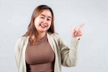 Neşeli genç bir kadın, parlak bir gülümsemeyle, gündelik tarzını sergileyen bir tarafı işaret ediyor. Bu ilgi çekici görüntü yaşam tarzı, sosyal medya ve pozitifliği ileten yaratıcı projeler için mükemmeldir.