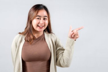 Neşeli genç bir kadın, parlak bir gülümsemeyle, gündelik tarzını sergileyen bir tarafı işaret ediyor. Bu ilgi çekici görüntü yaşam tarzı, sosyal medya ve pozitifliği ileten yaratıcı projeler için mükemmeldir.