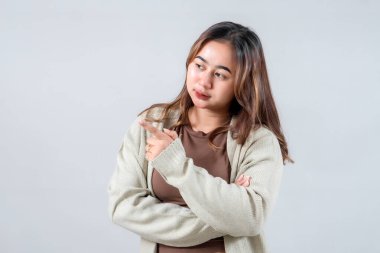 Genç bir kadın, yan tarafı gösterip, ilginç bir şey sunarken ışıl ışıl gülümsüyor. Onun gelişigüzel tarzı ve çekici ifadesi bu resmi yaşam tarzı ve promosyon projeleri için ideal kılıyor..