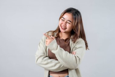 Genç bir kadın, yan tarafı gösterip, ilginç bir şey sunarken ışıl ışıl gülümsüyor. Onun gelişigüzel tarzı ve çekici ifadesi bu resmi yaşam tarzı ve promosyon projeleri için ideal kılıyor..