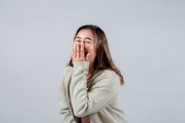 Genç bir kadın eliyle ağzını kapatarak yürekten güler. Onun gerçek mutluluk ifadesi ve gelişigüzel tarzı bu görüntüyü yaşam tarzı ve duygularla ilgili projeler için mükemmel kılıyor..