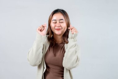 Genç bir kadın neşe dolu bir sürpriz yapar, gözleri açıktır ve elleriyle hareket ederken yüzünde bir gülümseme olur. Samimi bir süveter giyerek, heyecan ve mutluluğu simgeliyor..