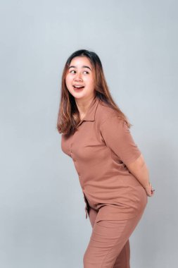 Gülümseyen genç Asyalı kadın, neşeli ve neşeli bir ifadeyle öne doğru eğiliyor. Açık ağzı ve ışıl ışıl gözleri kamerada heyecan, mutluluk ve dostça enerjiyi ifade eder..