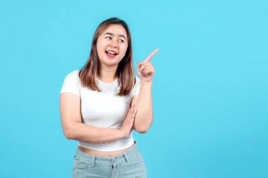 Gülümseyen neşeli genç bir kadın, parlak mavi bir arka plana karşı pozitif ve çekici bir ifade sergiliyor, yaratıcılığı ve ilhamı somutlaştırıyor.