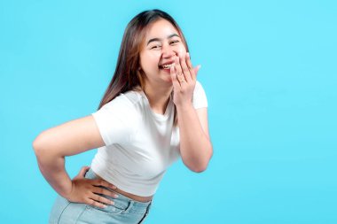 Neşeli genç bir kadın, açık mavi bir arka planda beyaz tişört ve kot şort giyerek neşeli bir şekilde gülüyor. Yaşam tarzı ve moda temaları için mükemmel.