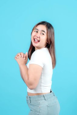 Beyaz tişörtlü neşeli genç bir kadın, dostane bir gülümseme ile, canlı mavi bir arka plan, sıcaklık ve yakınlık yayıyor.