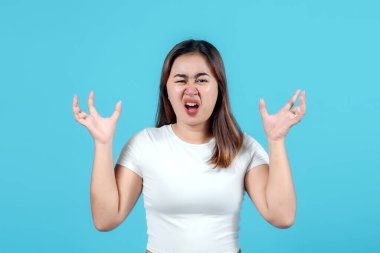 Beyaz kazaklı genç bir kadın şiddetli öfke ve hayal kırıklığını ifade eder. Yüzünde sert bir ifade ve el hareketleriyle.