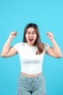 Beyaz bir bluz giymiş genç bir kadın öfke ve hayal kırıklığı sergiliyor, yumruklarını sıkıyor ve yüzünü buruşturuyor.