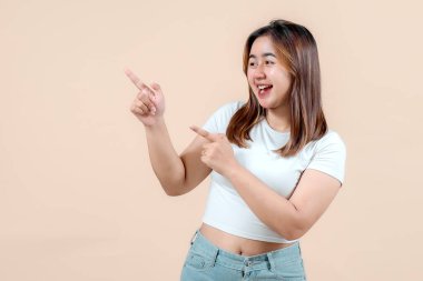 Neşeli, gülümseyen ve farklı yönleri işaret eden genç bir kadın. Yumuşak bir bej arka plan, coşku ve pozitiflik saçıyor..