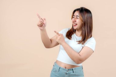 Neşeli, gülümseyen ve farklı yönleri işaret eden genç bir kadın. Yumuşak bir bej arka plan, coşku ve pozitiflik saçıyor..