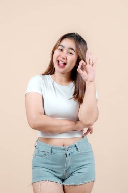 Neşeli genç bir kadın gülümseyerek ve elleriyle 