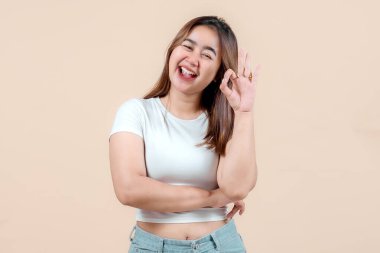 Neşeli genç bir kadın gülümseyerek ve elleriyle 