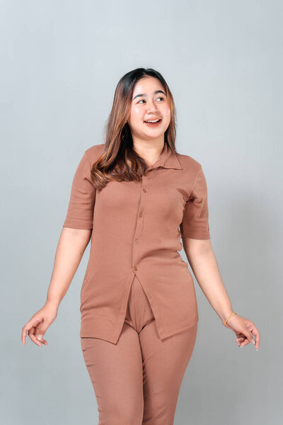 Charming young Asian woman smiling with an expression of surprise and delight while looking sideways. Her joyful face and natural pose convey curiosity, wonder, and positivity.