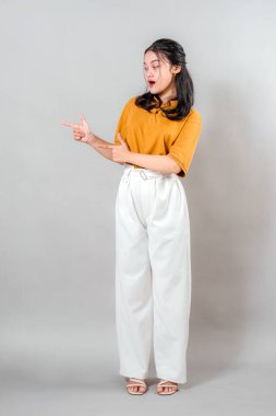 Şaşırmış ve şaşırmış bir yüz ifadesi olan Asyalı kadın, iki eliyle yüzünü işaret ediyor. Onun geniş gözlü tepkisi bu görüntüyü yaratıcı reklamcılık ve pazarlama içeriği için mükemmel kılıyor..