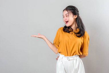 Heyecanlı, yüzü açık gülümseyen Asyalı genç bir kadın tek eliyle yüzünü göstererek yaratıcı reklamlar veya promosyon içerikleri için harika..