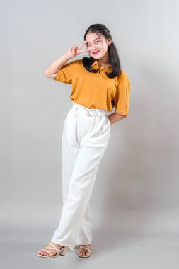 Neşeli, gülümseyen ve diş telleriyle sevimli bir barış işareti yapan Asyalı kadın. Neşeli ifadesi ve eğlenceli duruşu mutluluğu ve gençlik cazibesini yansıtıyor..