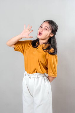 Çekici, Asyalı genç bir kadın güvenle gülümserken dostça bir selamla beş parmağını kaldırıyor. Onun anlamlı yüzü ve ışıl ışıl gülüşü sıcaklığı ve pozitif enerjiyi iletir..