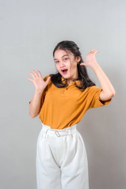 Şaşırmış genç Asyalı kadın ifade edici yüzü ve ağzı açık, iki elini de yüzüne kaldırıyor. Neşeli tepkisi ve şaşkın bakışları gerçek duygu ve heyecanı gösteriyor..