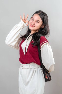 Hoş bir el hareketiyle gülümseyen genç Asyalı kadın. Güven, pozitiflik ve sıcaklık yayar. Reklam, markalaşma veya tanıtım içeriği için ideal.