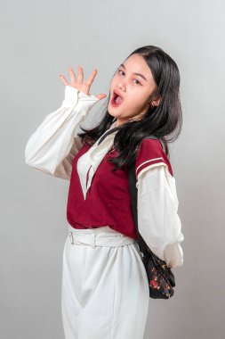 Şaşırmış ve neşeli bir yüz ifadesi olan enerjik genç Asyalı kadın, ağzı açık ve eli havada. Etkileyici ve eğlenceli poz, promosyon ve reklam içeriği için mükemmel.