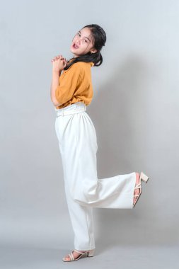 Neşeli genç kadın neşeli bir şekilde gülümsüyor, stüdyo çekimlerinde mutluluğu ve eğlenceyi ifade ediyor..